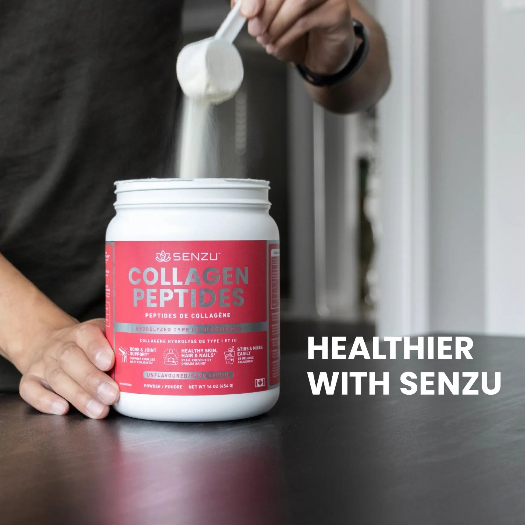 A hand scoops white Collagen Peptides Protein Powder (454g) from a Senzu Health container on a dark countertop, with the text Healthier with Senzu. Made with grass-fed collagen, ideal for a keto-friendly lifestyle.